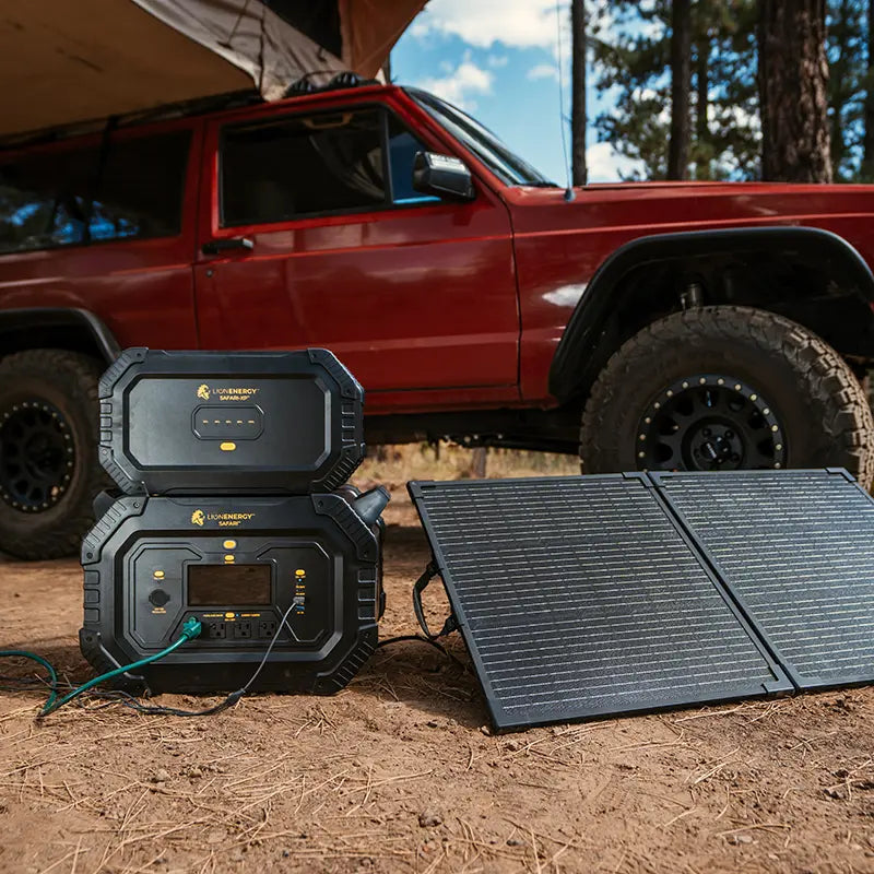 A Lion Safari and Safari XP charging from folding solar panels beside a truck